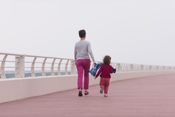 mother and cute little girl on the promenade by the sea