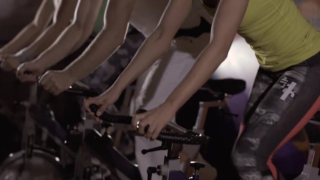 Close-up of three people working out on stationary bikes at fitness center