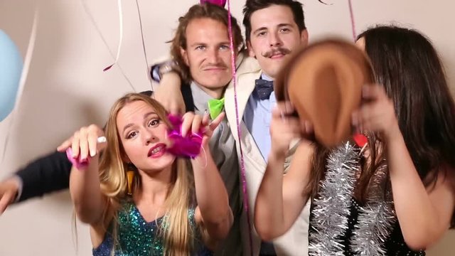 Two young cute couples having fun in party photo booth 