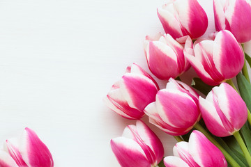 Fototapeta premium Happy Mother’s Day concept - pink tulips and turquoise or teal colour hear shape lantern with a candle against white wooden background