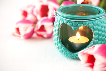 Obraz na płótnie Canvas Happy Mother’s Day concept - pink tulips and turquoise or teal colour hear shape lantern with a candle against white wooden background