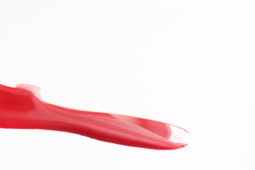 Vibrant flowing glossy and shiny red nail polish with sparkling glitter isolated on white background with free space. Art, creativity, modern abstractionism.