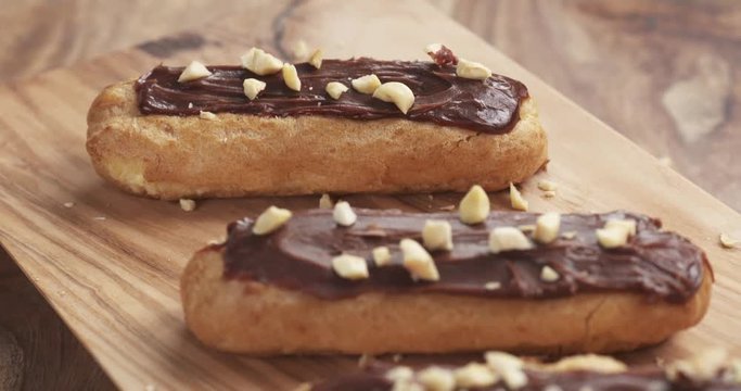 Slow motion of backward fly over eclairs with hazelnuts on wood board, 4k 60fps prores footage