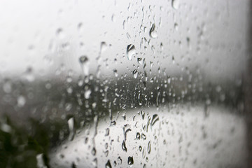Rain drops on a grey window glass surface