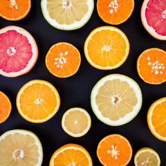 Fototapeta premium Lemon, orange, mandarin and grapefruit on black background. Flat lay, top view. Fruit colorful background