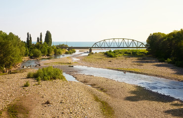Fototapeta premium Railway bridge across the river, flowing into the sea