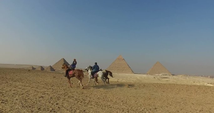 CAIRO, EGYPT - 04 FEBRUARY 2016: Young woman on horse galloping fast with local man at Giza pyramids complex