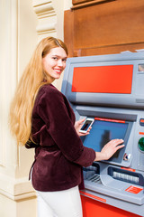Fototapeta na wymiar Blonde woman on the background in shopping center ATM