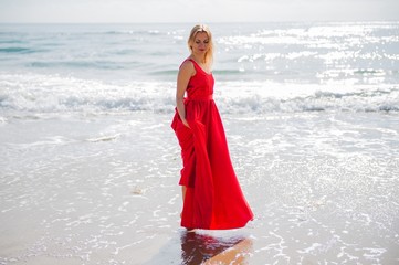 Fototapeta na wymiar Beautiful blonde woman with red dress in the beach