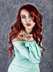 fashion portrait of redhead model posing near gray wall, girl with big tits in a tight dress