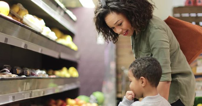 Mother and son buying fruit and vegetables in grocery store
