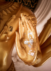 Closeup of open hand of Buddha with silver leaf in buddhist temple in Thailand