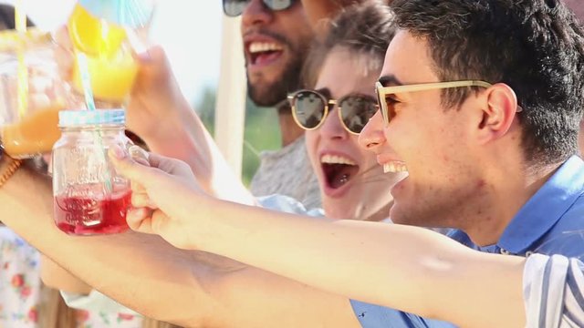 Close up of cheerful friends laughing and toasting at rooftop party 