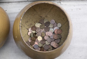 Golden alms bowl with little thai coins inside in buddhist temple in thailand