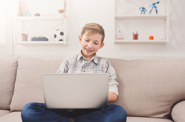 Teenage boy using laptop on couch at home