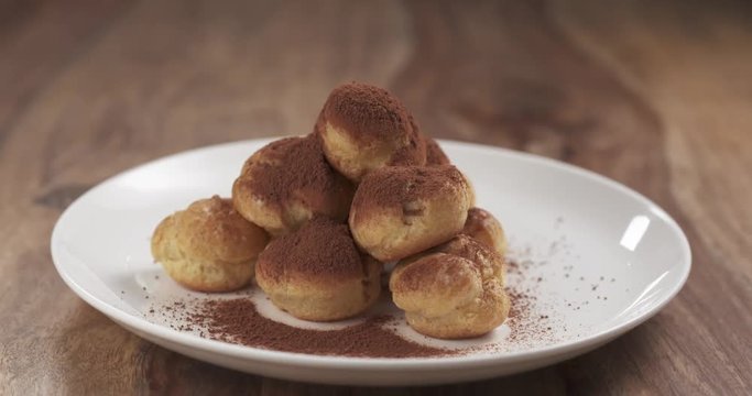 profiteroles with cocoa powder pan reveal on table, 4k prores footage