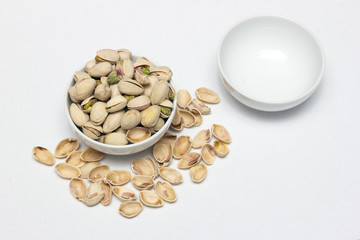 One bowl filled with pistachios and the other is empty.