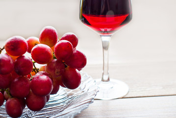 Grape wine in a glass cup, a bunch of grapes with a light background.
