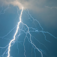Naklejka na ściany i meble Fork lightning against blue sky on stormy summer day