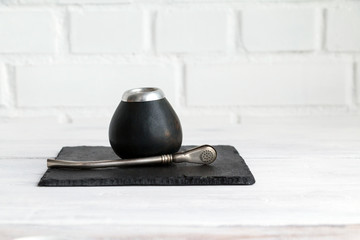 Traditional calabash gourd for mate tea drinking with straw on slate / white table. Copy space.