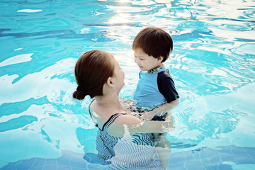 Mother and her son having fun in the swimming pool at sunset : Soft Focus