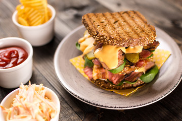 Big Homemade Sandwich with Roast Beef, Bacon, Pickles, Baby Spinach and Coleslaw Dressing in Toasted Bread