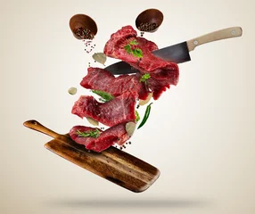 Keuken foto achterwand Vlees Vliegende rauwe steaks met ingrediënten, voedselbereidingsconcept