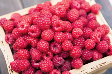 Basket with raspberries on wooden table