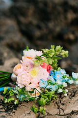Obraz na płótnie Canvas Wedding bouquet of peonies on the rocks by the sea. Wedding in Montenegro.