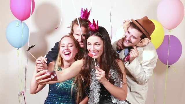 Group of funny crazy friends taking selfie in party photo booth