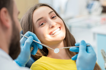 Portrait of a woman with toothy smile sitting during examination at the dental office