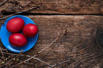 Three Easter eggs, on a blue plate in the nest with spring branches