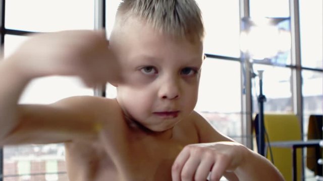 Young boy training to box bare hands to the camera - slow motion