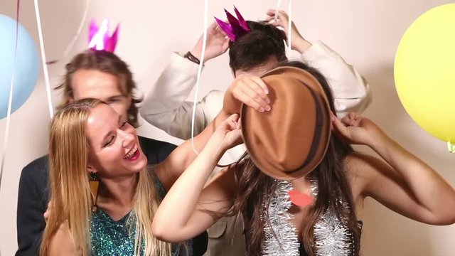 Group of four cheerful friends making funny faces in party photo booth 