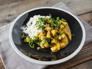 Delicious turkey mango curry with rice on a black plate