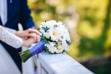 Wedding bouquet on the background of the hand of the bride and groom