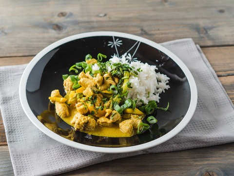 Delicious turkey mango curry with rice on a black plate