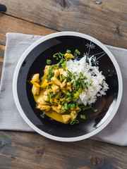 Delicious turkey mango curry with rice on a black plate