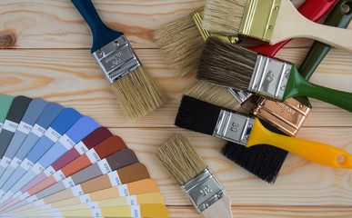 Painter and decorator work table with house project, color swatches, painting roller and paint brushes