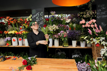 Kobieta, sprzedawca w kwiaciarni trzyma kwiaty.