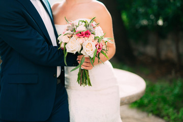 Wedding bouquet of roses, peonies and succulents in the hands of the bride. Wedding in Montenegro.