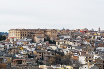 A view of Toledo old town, medieval buildings with tile roofs, churches and a building of Seminario Conciliar San Ildefonso.