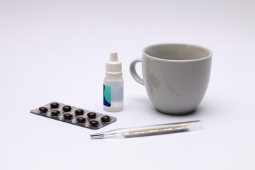 Medicines and medicines for colds. Pills, drops, glass of water, thermometer on white background.