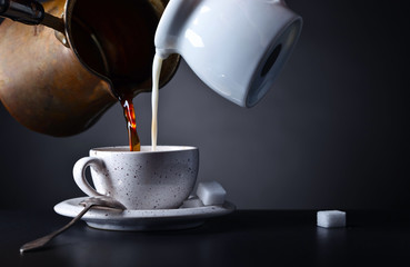 Cup of coffee with milk and sugar on dark background