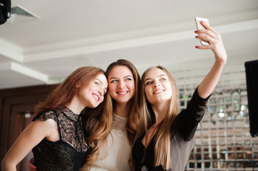 Three young girls are doing selfie photo in a restaurant