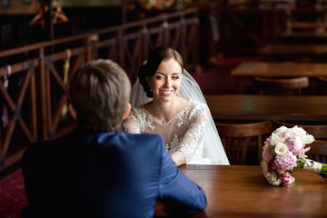 Bride and groom sitting in cafe and looking at each other like at first date