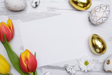 Easter eggs and tulips over wooden background.
