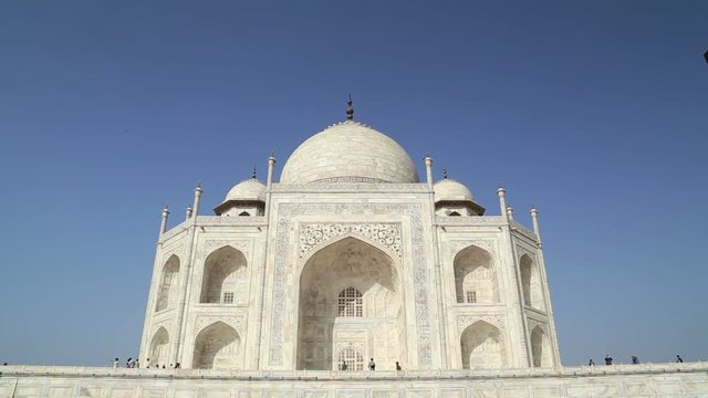 Outdoor wall of Taj Mahal, with people passing in front.