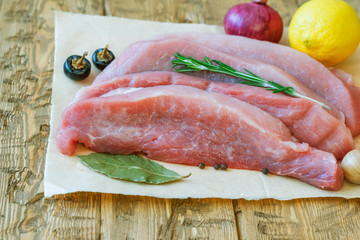 Pork with cherry tomatoes and lemon on a wooden table.