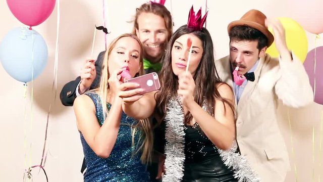 Group of beautiful happy friends taking selfie in photo booth, graded